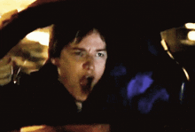 a woman is yawning while driving a car