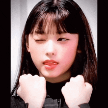 a girl with long hair and bangs is making a funny face with her tongue out .
