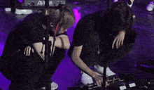 two people kneeling in front of a microphone that says avi on it