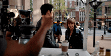 a man is taking a picture of a woman with a cup of coffee in front of a cw logo