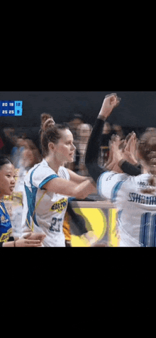 a group of female basketball players are giving each other a high five .