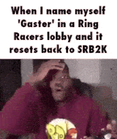 a man in a red hoodie is sitting on a couch with his hands on his head .