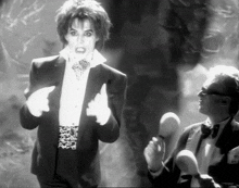 a black and white photo of a man in a tuxedo standing next to another man in a tuxedo