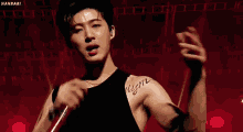 a young man with a tattoo on his arm is singing into a microphone on a stage .
