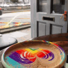 a cup of coffee with a rainbow swirl on top of it