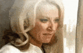 a woman with blonde hair is looking out of a window and making a funny face .