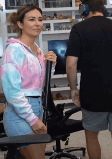 a woman in a tie dye hoodie stands next to a man in a black shirt