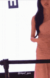 a woman in a pink dress is standing in front of a sign that says h.