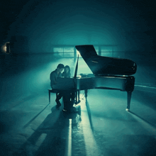 a man and a woman are sitting at a piano in a dark room