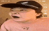 a man wearing a hat and a pink shirt is making a surprised face .