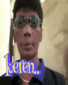 a man wearing sunglasses and a blue shirt with the word keren on the bottom right