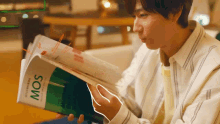 a man is reading a book with the word mos on the cover