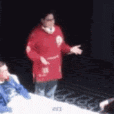 a blurry picture of a man in a red sweater standing in front of a group of people .