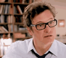 a man wearing glasses and a white shirt and tie is making a funny face .