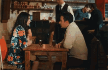 a man and a woman are sitting at a table in a restaurant talking to each other