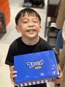 a young boy is holding a blue tough kids box