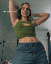 a woman in a green top and blue jeans is dancing