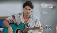 a man is playing a guitar in front of a screen that says colors