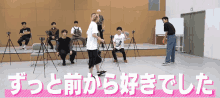 a group of people are standing and sitting in a room with japanese writing on it