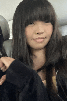 a girl with long black hair and bangs is smiling