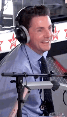 a man wearing headphones stands in front of a virgin radio banner