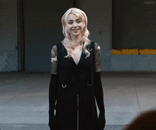 a woman in a black dress and black gloves smiles in front of a kepler sign