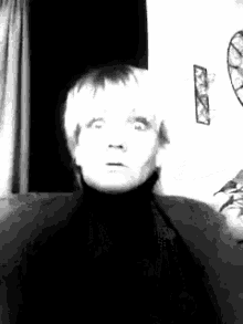 a black and white photo of a woman sitting on a couch making a funny face .