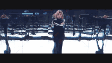 a woman in a red suit is dancing in front of a mirrored wall