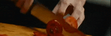 a person is cutting a tomato on a cutting board .