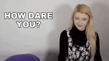 a woman is asking how dare you while wearing a black turtleneck