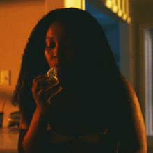 a woman in a dark room is eating a piece of food