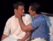 a man in a hospital gown is touching another man 's neck