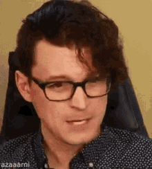 a close up of a man wearing glasses and a polka dot shirt .
