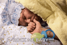 a baby with a pacifier in its mouth is sleeping under a blanket with the words rock me baby written on the bottom