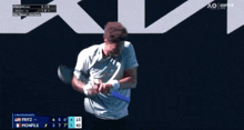 a man holding a tennis racquet in front of a sign that says ao