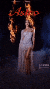 a woman in a white dress is standing in front of a fire and the word astro
