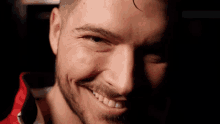a close up of a man 's face with a red jacket on