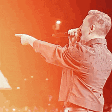 a man singing into a microphone with his finger pointing
