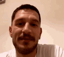 a man with a beard and earrings is smiling and looking at the camera