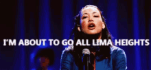 a woman is singing into a microphone with the words `` i 'm about to go all lima heights '' behind her