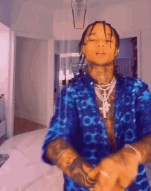 a man wearing a blue shirt and a cross necklace is dancing