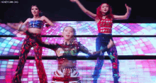 three women are dancing on a stage with a disco ball in the background .