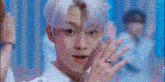 a young man with white hair and a ring on his finger is smiling while dancing .