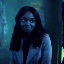a woman with long black hair is wearing a grey jacket and black shirt