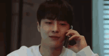 a young man is smiling while talking on a cell phone .