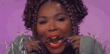 a woman with curly hair and red lipstick is eating a piece of food with a fork .