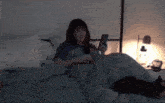 a woman is laying in bed looking at her cell phone