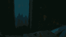a man in a gray shirt is sitting in a dark room .