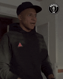 a man wearing a black hoodie and a black hat with the word mbappe live on it