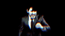 a man in a suit and tie is standing in the dark with his arms outstretched .